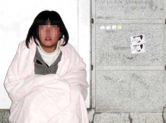 Young fans in blankets waiting outside a venue for a Korean idol group, illustrating the dedication of early K-pop fans.